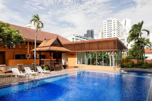 a swimming pool with chairs and a building at Teja Hotel in Bangkok