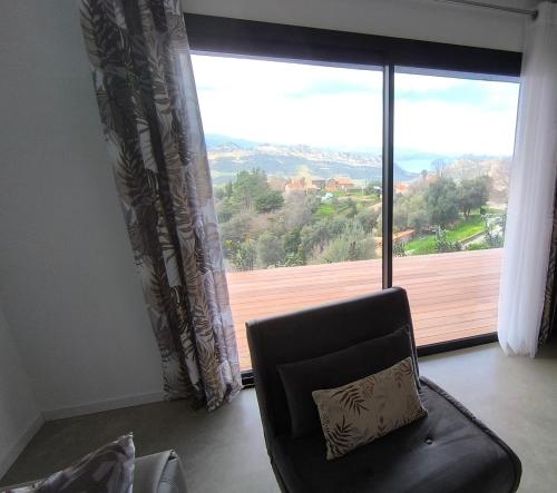 einen Stuhl mit einem Kissen vor einem großen Fenster in der Unterkunft Chambre entre mer et montagne in Barbaggio