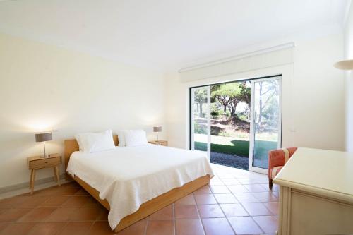 a white bedroom with a bed and a sliding glass door at Casa Atlantico in Quinta do Lago