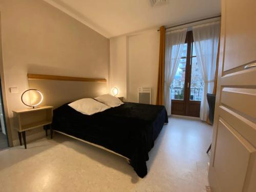 L'Ecrin de Verdure du Centre Ville في إيكس لي بان: غرفة نوم بسرير اسود ونافذة