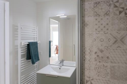 Un baño con lavabo, espejo y ducha. en Appartement neuf à 5 minutes à pied de la plage, en Barbâtre