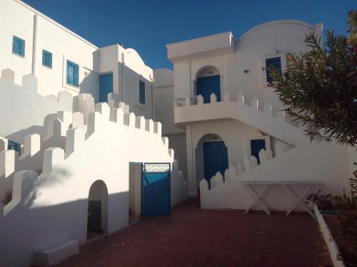 a building with white walls and a blue door at taguermess 2 in Midoun