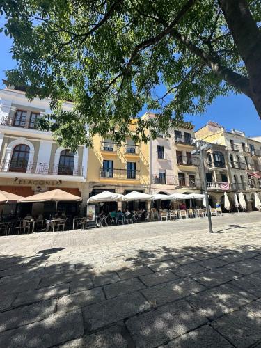 a group of buildings with tables and umbrellas at Lovely 2 bedrooms apartment main square Plasencia in Plasencia