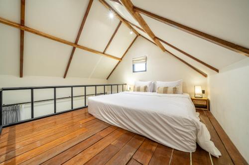 a bedroom with a white bed and a wooden floor at Reconnect in Ubud - Peaceful Living at Sarang Apartments 1 in Ubud