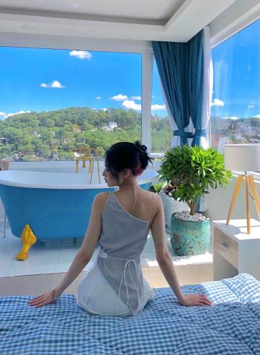 a woman sitting on a bed in front of a bath tub at Homey Home Đà Lạt in Da Lat