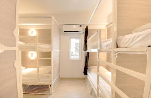a room with white bunk beds in it at The Ostel Hostel Bangkok in Bangkok