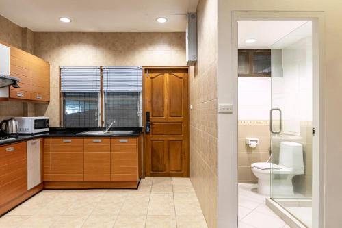 a kitchen with wooden cabinets and a toilet and a sink at Teja Hotel in Bangkok