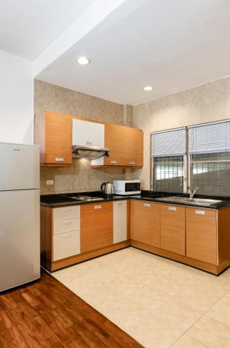 a kitchen with wooden cabinets and a white refrigerator at Teja Hotel in Bangkok