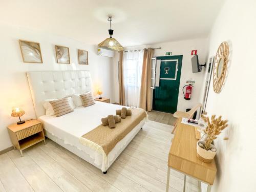 a bedroom with a white bed and a green door at Casa da Alagoinha by Umbral in Vila Nova de Milfontes