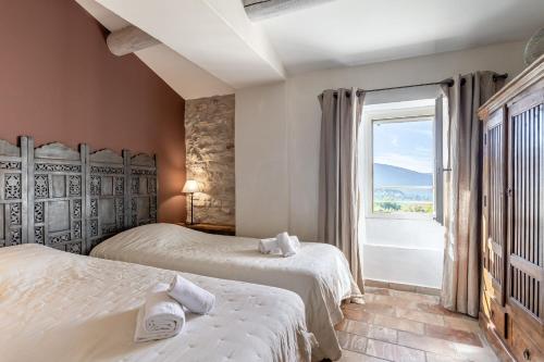 a bedroom with two beds and a large window at Le Major in Cadenet