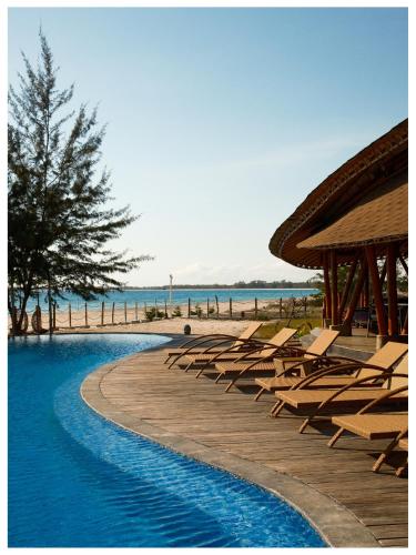 a swimming pool with lounge chairs and the beach at Tanoma Sumba in Maujawa