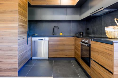 a kitchen with wooden cabinets and a dishwasher at Chalés Avelino Carolino ll com Roteiro incluído in Chaves