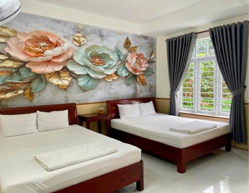 2 letti in una camera con un dipinto sul muro di Nhà Nghỉ Kim Phượng Vũng Tàu a Vung Tau