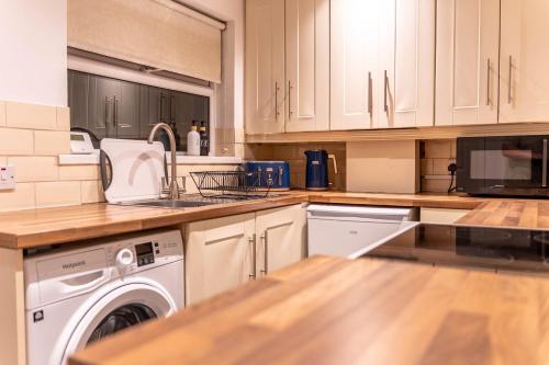 a kitchen with white cabinets and a washer and dryer at Lodging in Carrickfergus in Carrickfergus