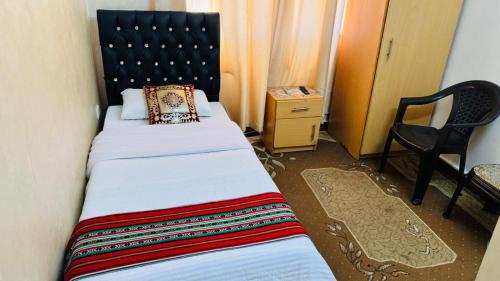 アンマンにあるNew Hamoudeh Hotelのベッドと椅子のある小さな寝室