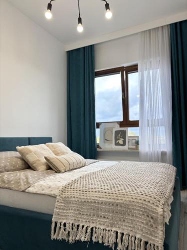 1 dormitorio con 1 cama con cortinas azules y ventana en Wilanów Residence - Two-Room Apartment, en Varsovia