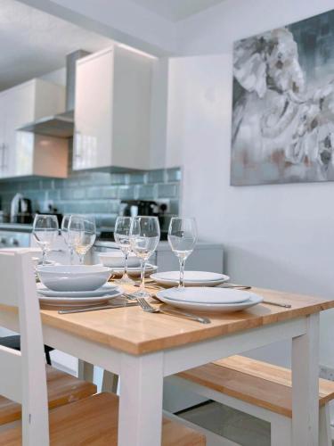 a wooden table with wine glasses and plates on it at Modern 3-bed house with parking - Chorley Near M61 in Heapey
