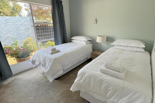 zwei weiße Betten in einem Schlafzimmer mit Fenster in der Unterkunft Cottage - Sleeps 4 - Pet friendly - Pool - Parking in Johannesburg