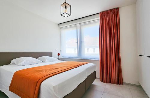 a bedroom with a large window and a bed with an orange blanket at Appartement Porte Bonheur in Rochefort