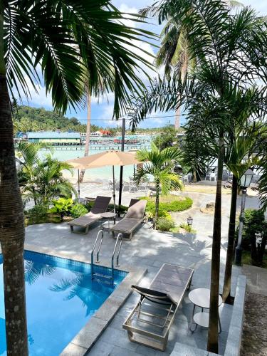 Una piscina con sillas y sombrilla y palmeras. en Lanting Villas, en Koh Rong