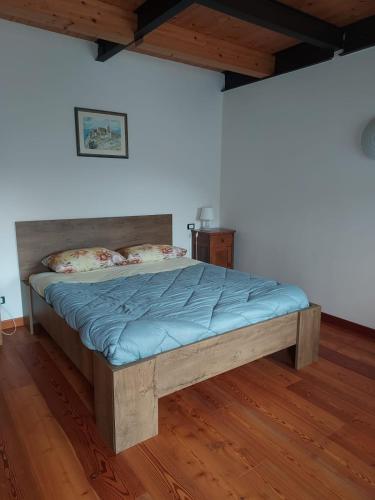 a bed in a bedroom with a wooden floor at Agriturismo Coi de Pera in Ponte nellʼAlpi