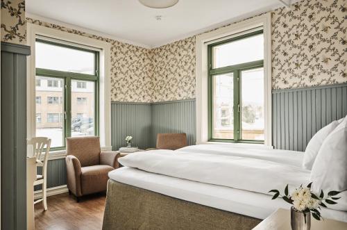 a bedroom with a large bed and two windows at Fru Haugans Hotel in Mosjøen