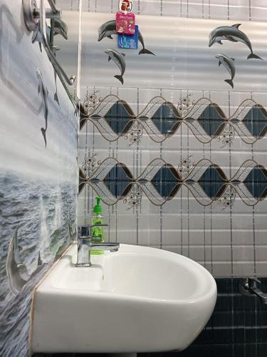 a white sink in a bathroom with birds on the wall at Shruthi's Aarohi-Nature's Retreat Homestay in Kannur
