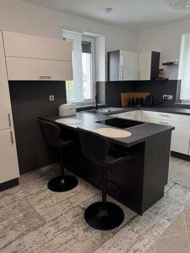 une cuisine avec un îlot noir et deux tabourets de bar dans l'établissement Perviz, à Braunau am Inn