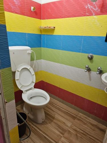 a bathroom with a toilet and a colorful wall at Hotel Seven Heaven in mayapur