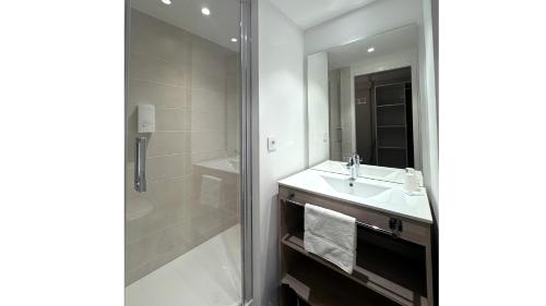 a white bathroom with a sink and a shower at Villages Clubs du Soleil - LES MENUIRES in Les Menuires