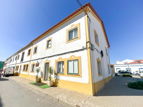 a yellow and white building on the side of a street at Casa da Alagoinha by Umbral in Vila Nova de Milfontes