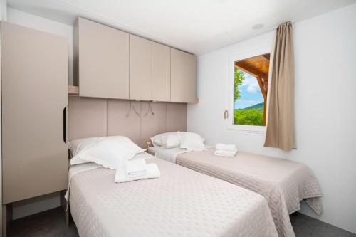 two beds in a room with a window at KAPO Mobile Home in Sitno Donje