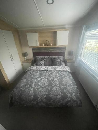 a bedroom with a large bed and a window at Beautiful caravan at Kent coast with wrap around decking and free WiFi sleeps 6 in Allhallows