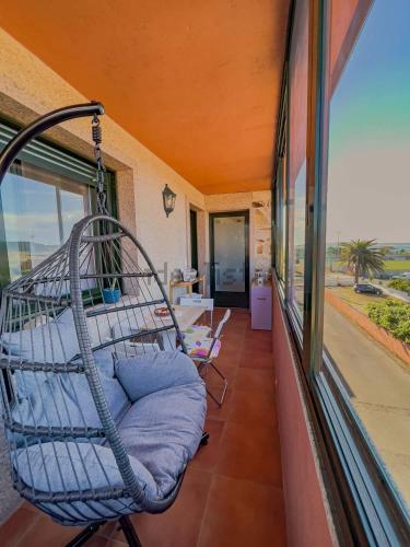 un porche con una silla mecedora en el balcón en A Lanzada Con Amor, en Sanxenxo