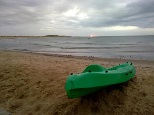 a green boat sitting on the sand on the beach at Casa Grande in Galinhos