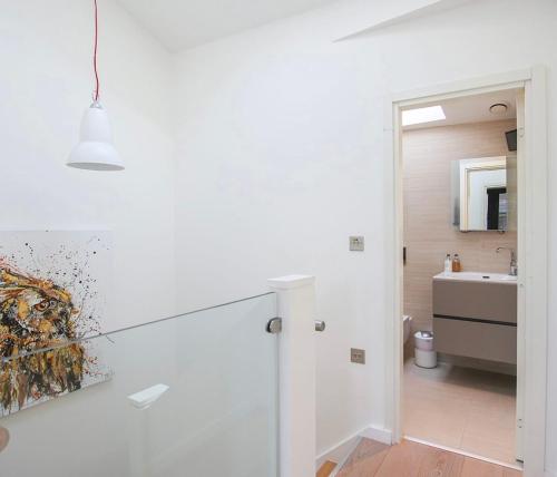 a white bathroom with a sink and a mirror at Escape to Infinity! in Guernsey
