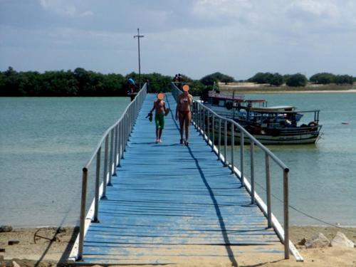 a man and a child walking on a bridge over the water at Casa Grande in Galinhos