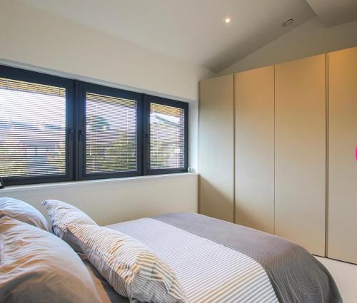 a bedroom with a bed and two windows at Escape to Infinity! in Guernsey