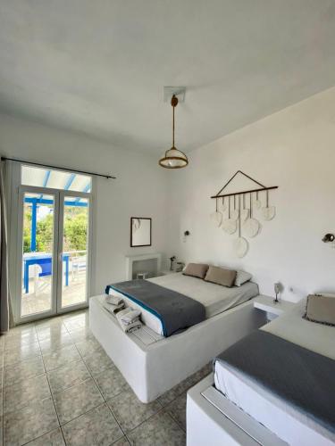 a white bedroom with two beds and a chandelier at Venetos Studios in Livadi Astypalaias