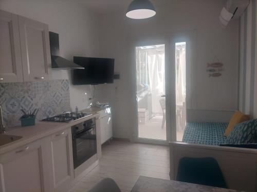 a kitchen with white cabinets and a door to a patio at Da BeA in Villasimius