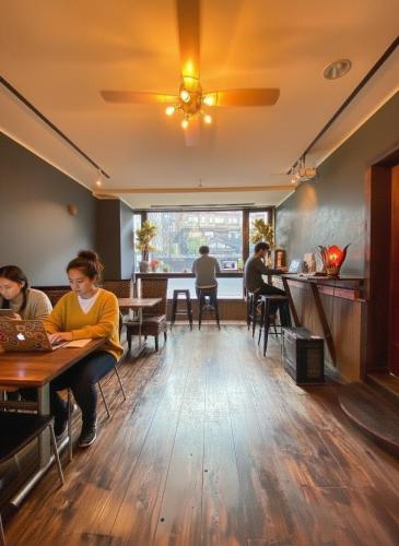 a group of people sitting at tables in a restaurant at Kaido Yuzawa Onsen Hostel in Yuzawa