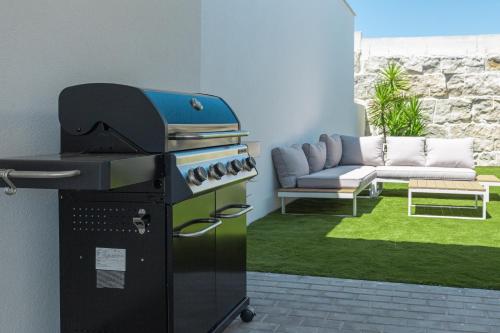 a patio with a grill and a couch in a yard at Villa Laura with private swimming pool in Lourinhã
