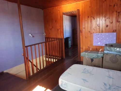 Habitación con escalera de madera y cama. en casa verde 2 pisos, en Rivera