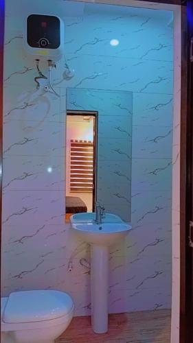 a bathroom with a sink and a toilet and a mirror at Less2More Luxury Suites in Agege