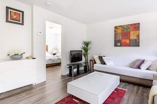 a white living room with a couch and a tv at Logement neuf, spacieux in Longueuil