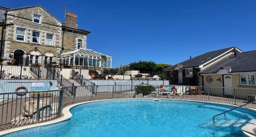 a swimming pool in front of a house with a fence at Sure Hotel Collection by Best Western Porth Veor Manor Hotel in Newquay