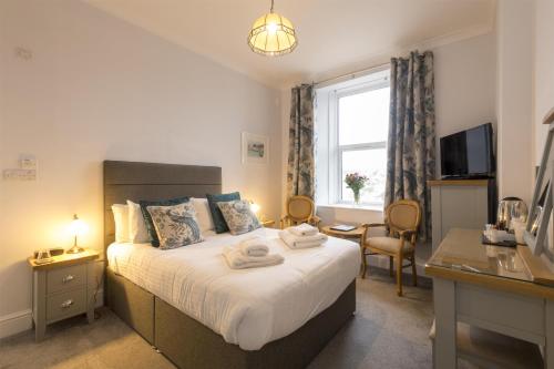 a bedroom with a bed with a desk and a window at Sure Hotel Collection by Best Western Porth Veor Manor Hotel in Newquay