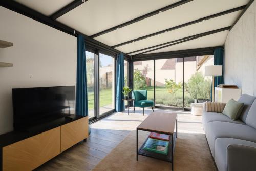 ein Wohnzimmer mit Sofa und Fernseher in der Unterkunft Le Relais d'Ezy - 3 chambres in Ézy-sur-Eure