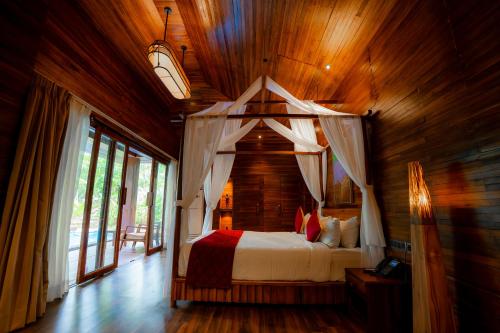 a bedroom with a canopy bed in a wooden room at De Foret in Havelock Island