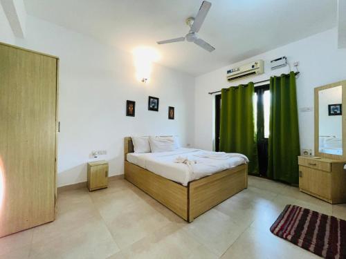 アーポラにあるPS Villa 3bhk Bagaのベッドルーム(ベッド1台、緑のカーテン付)